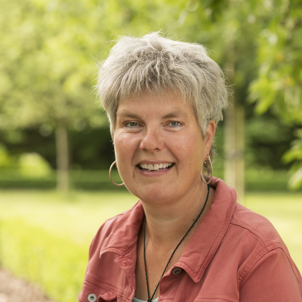 Portret van een vrouw buiten, met bomen op de achtergrond